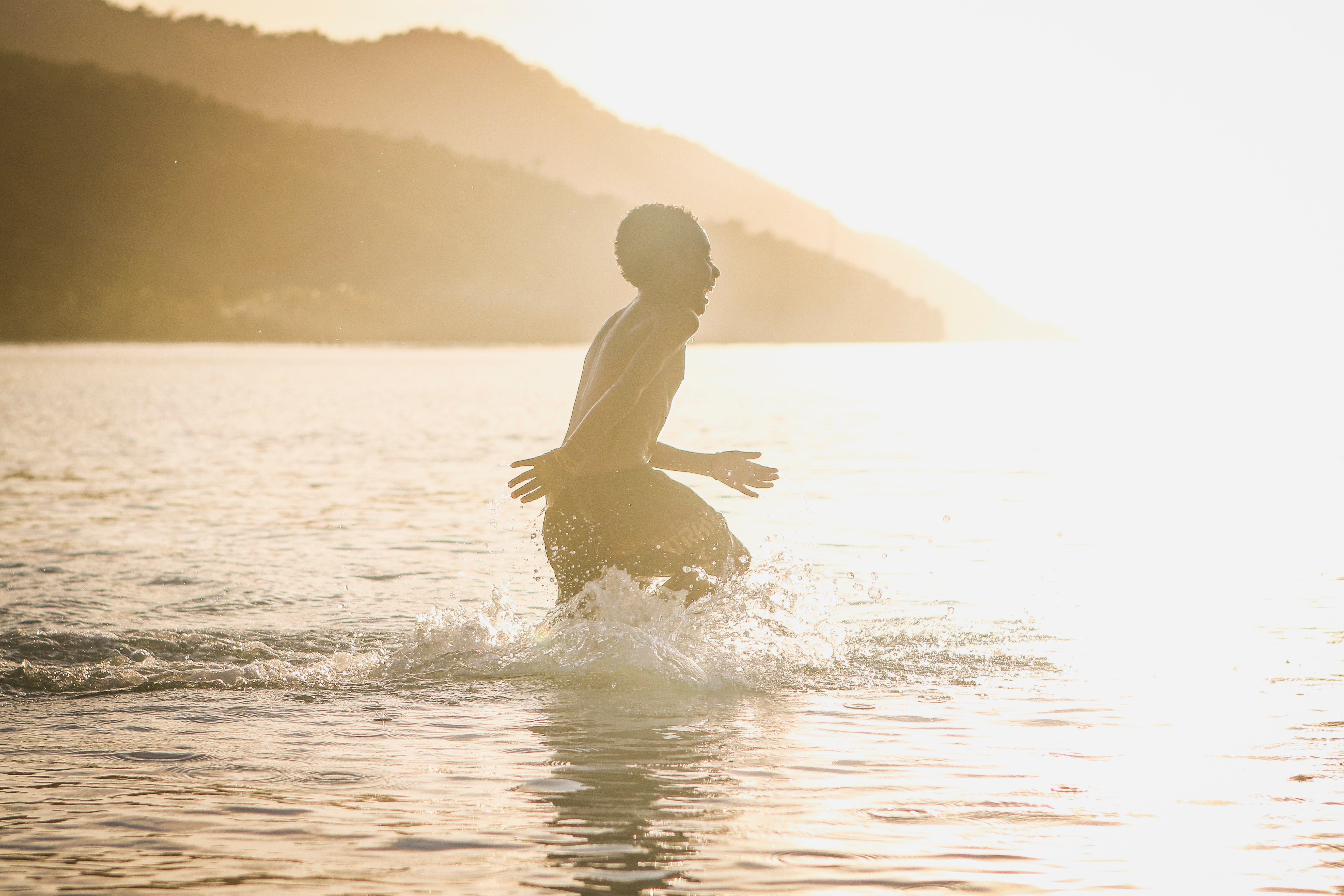 A child playing in the sea at sunset